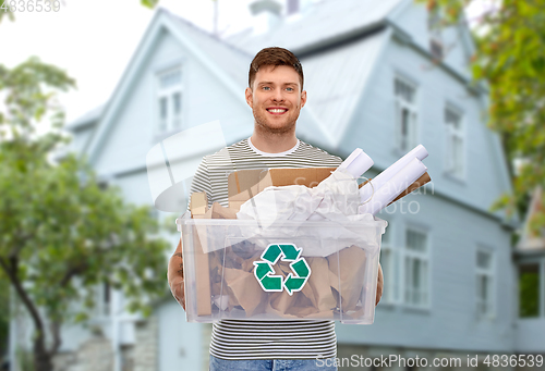 Image of smiling young man sorting paper waste over house