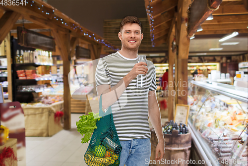 Image of man with food in bag and water in glass bottle