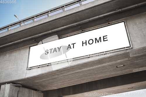 Image of billboard with stay at home words on bridge