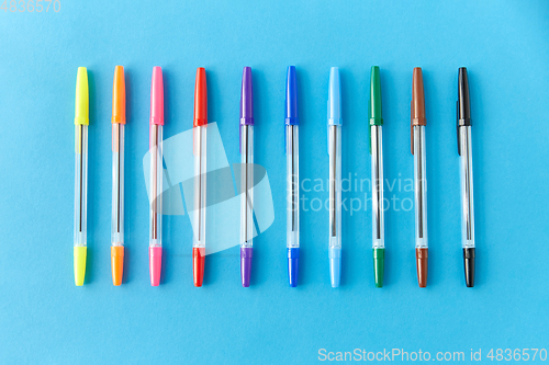 Image of row of multicolored pens on blue background