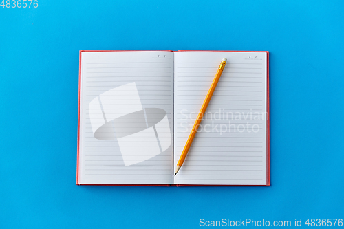 Image of open notebook with pencil on blue background