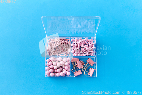 Image of pins and clips in plastic pox on blue background