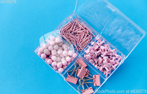 Image of pins and clips in plastic pox on blue background