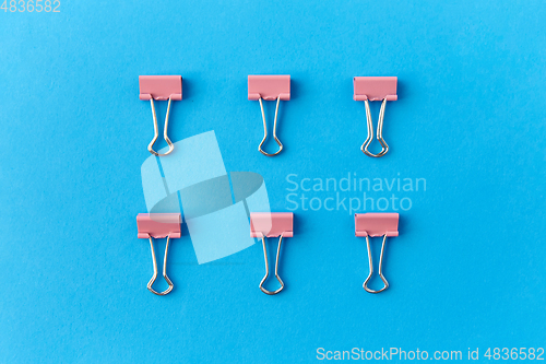 Image of office binder clips on blue background