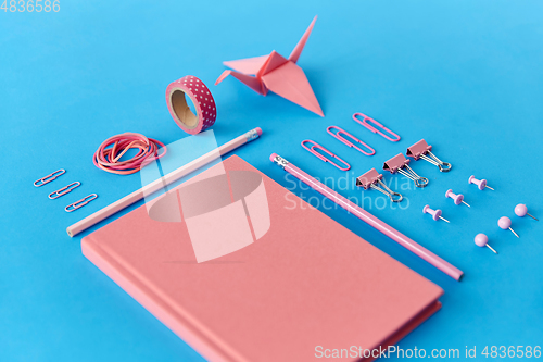 Image of pink notebook, pins, clips, pencils and rubbers