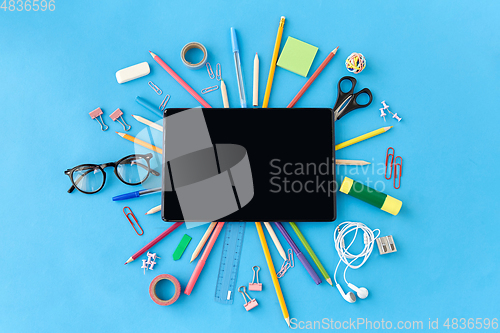 Image of tablet pc and school supplies on blue background