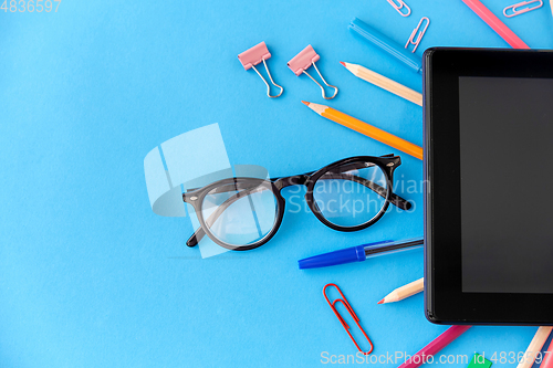 Image of tablet pc and school supplies on blue background