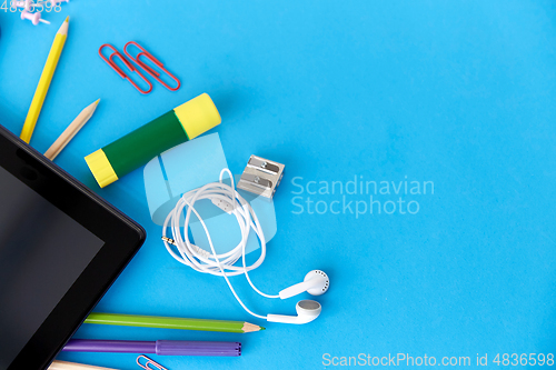 Image of tablet pc and school supplies on blue background