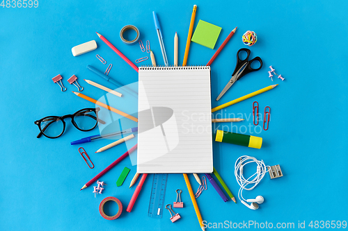 Image of notebook and school supplies on blue background