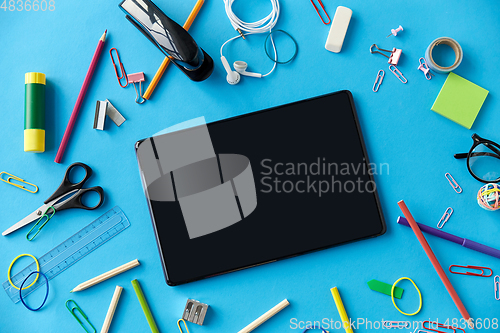 Image of tablet pc and school supplies on blue background