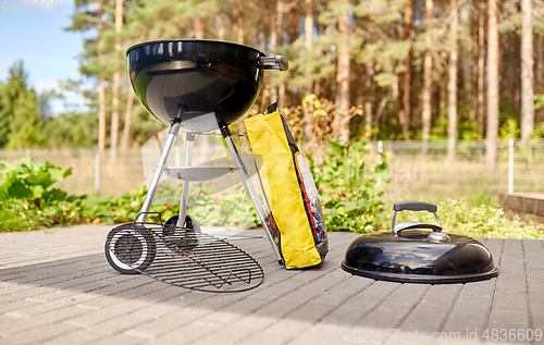 Image of bbq grill brazier and bag of charcoal outdoors