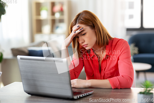 Image of stressed woman with laptop working at home office