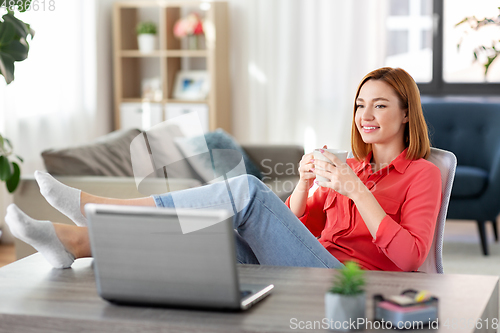 Image of woman with laptop drinking coffee at home office