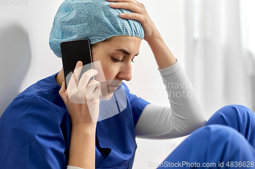 Image of sad doctor or nurse calling on smartphone