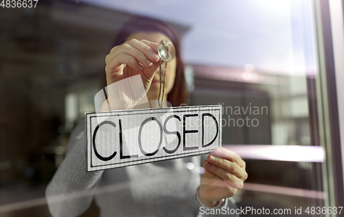 Image of woman hanging banner with closed word on door