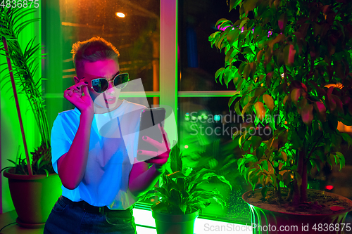 Image of Cinematic portrait of handsome young woman in neon lighted interior