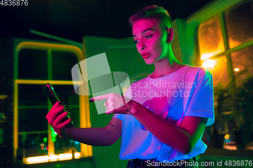 Image of Cinematic portrait of handsome young woman in neon lighted interior