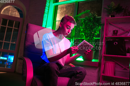 Image of Cinematic portrait of handsome young woman in neon lighted interior