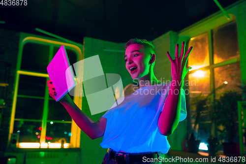 Image of Cinematic portrait of handsome young woman in neon lighted interior