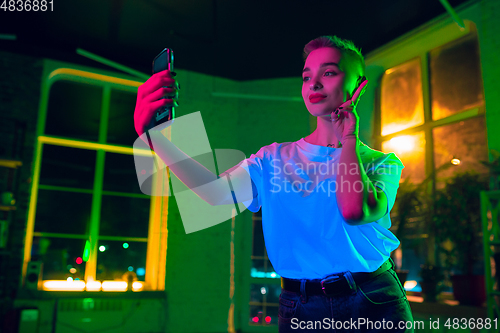 Image of Cinematic portrait of handsome young woman in neon lighted interior