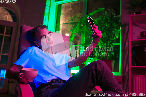 Image of Cinematic portrait of handsome young woman in neon lighted interior