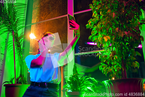 Image of Cinematic portrait of handsome young woman in neon lighted interior