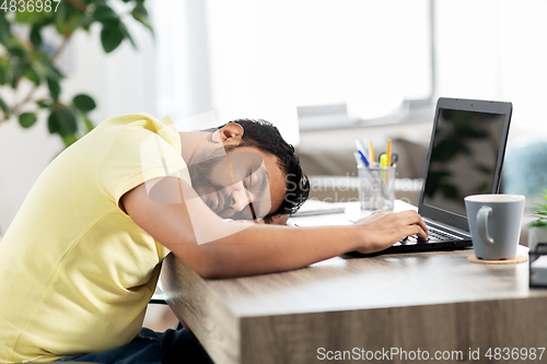 Image of indian man sleeping on table with laptop at home