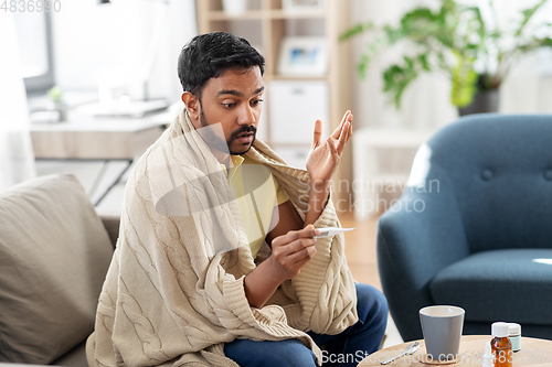 Image of sick man measuring temperature by thermometer