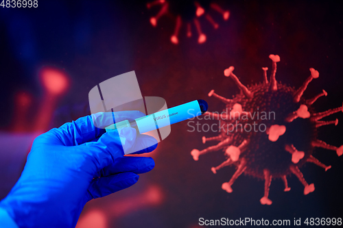 Image of hand holding beaker with coronavirus blood test