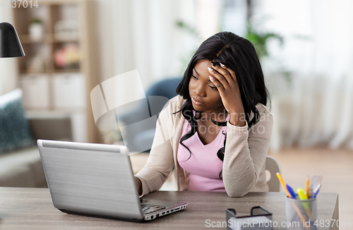 Image of stressed woman with laptop working at home office