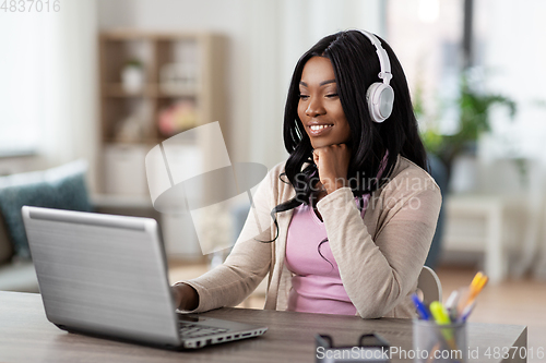 Image of woman in headphones with laptop working at home