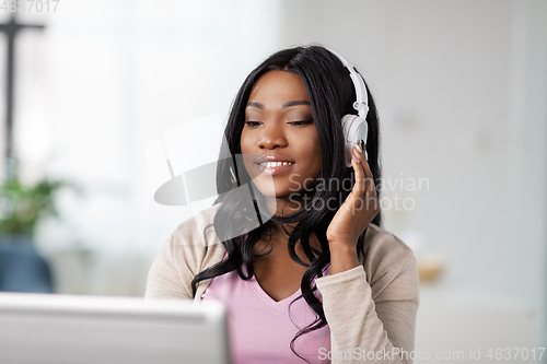 Image of woman in headphones with laptop working at home