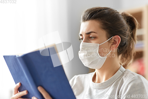 Image of sick woman in medical mask reading book at home