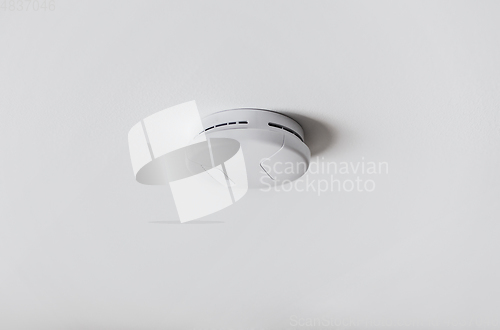 Image of smoke alarm, sensor or detector on white ceiling