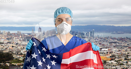 Image of doctor in goggles and mask holding flag of america