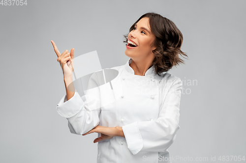 Image of smiling female chef in toque pointing finger up