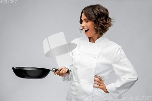 Image of smiling female chef in toque with frying pan