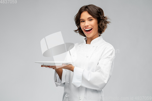 Image of smiling female chef holding empty plate