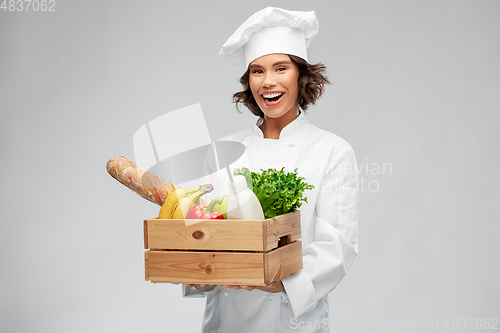 Image of happy smiling female chef with food in wooden box