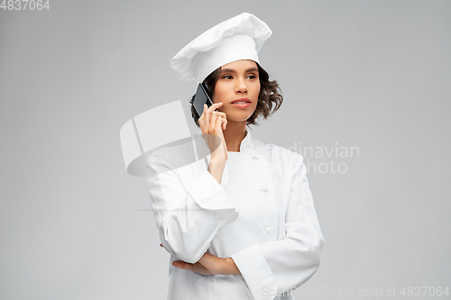 Image of female chef in toque calling on smartphone