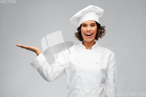 Image of smiling female chef holding something on hand