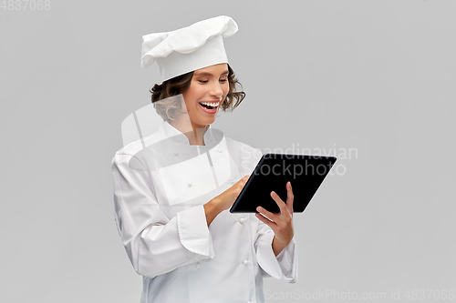 Image of smiling female chef in toque with tablet computer