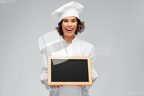 Image of smiling female chef holding black chalkboard