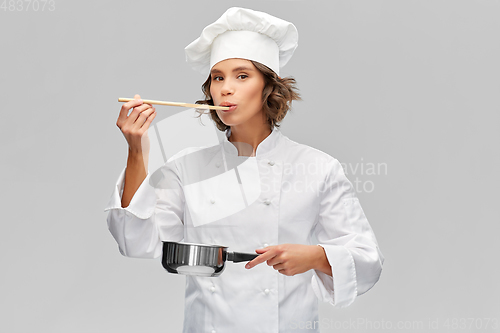 Image of female chef with saucepan tasting food