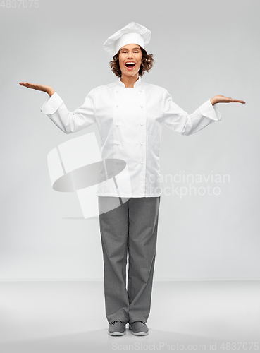 Image of smiling female chef holding something on hand