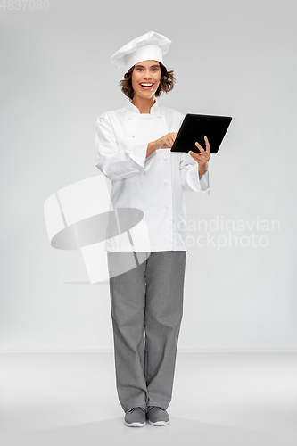 Image of smiling female chef in toque with tablet computer