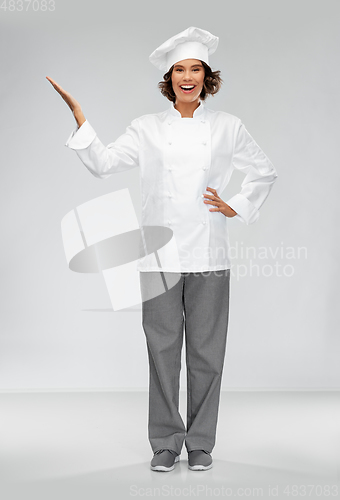 Image of smiling female chef holding something on hand