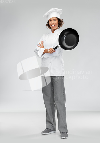 Image of smiling female chef in toque with frying pan