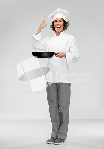 Image of smiling female chef with frying pan showing ok