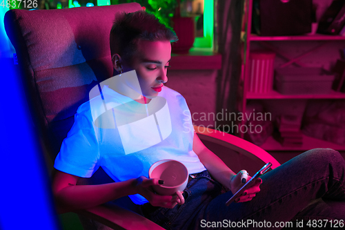 Image of Cinematic portrait of handsome young woman in neon lighted interior